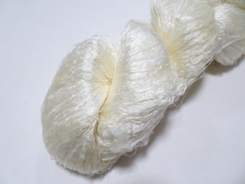 May include: A skein of white silk yarn with a soft, fluffy texture.