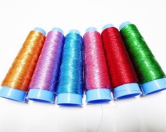 May include: Six spools of metallic thread in various colors, including orange, purple, blue, pink, red, and green. The spools are all wrapped in blue plastic.