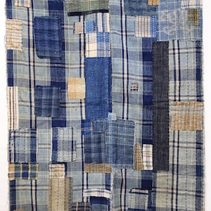 Puede incluir: Obra de arte textil en patchwork en tonos azules. El diseño incorpora varios tejidos, incluyendo secciones a cuadros y lisas, cosidas juntas. La pieza muestra una gama de tonos y texturas azules, creando una composición visualmente rica.