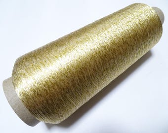 May include: A spool of gold metallic thread. The thread is wound around a cardboard spool.