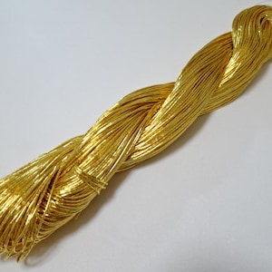 Puede incluir: Un carrete de cordón metálico dorado, retorcido y enrollado, listo para proyectos de manualidades.