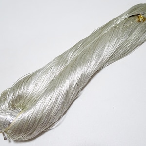 May include: A spool of silver metallic thread. The thread is tightly wound and has a shiny, reflective finish.
