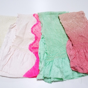 May include: An assortment of colorful, textured fabric pieces. The fabrics are in shades of cream, pink, and green, with a ruffled edge on some. The textures include a ribbed and patterned design.