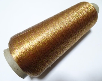 May include: A spool of gold metallic thread with a brown cardboard base.