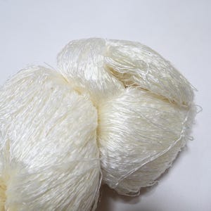 May include: A skein of white silk yarn, soft and fluffy, perfect for knitting or crocheting delicate projects.