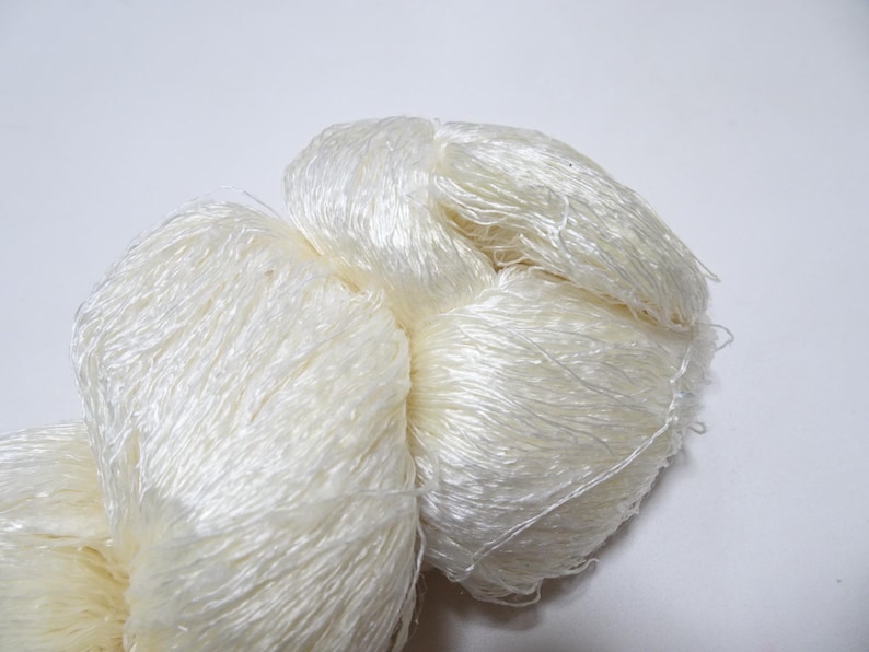 May include: A skein of white silk yarn, soft and fluffy, perfect for knitting or crocheting delicate projects.