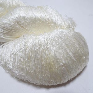 May include: A close-up of a white, fluffy yarn. The yarn is soft and delicate, and it is perfect for knitting or crocheting.