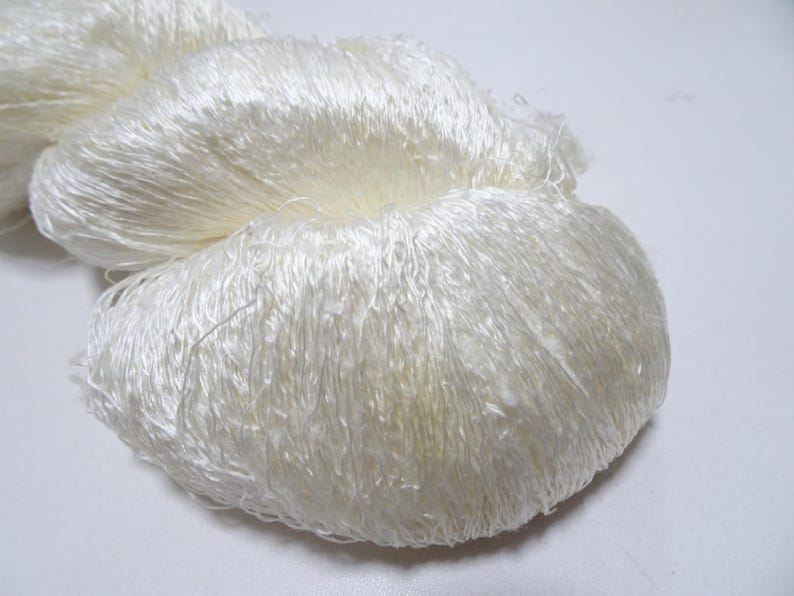May include: A close-up of a white, fluffy yarn. The yarn is soft and delicate, and it is perfect for knitting or crocheting.
