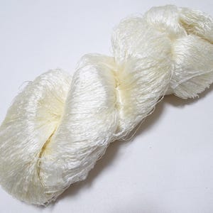 May include: A skein of white silk yarn, soft and fluffy, ideal for knitting or crocheting delicate projects.
