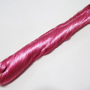 Puede incluir: Una bobina de hilo de seda rosa.