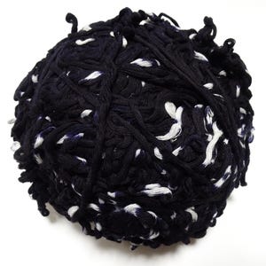 Può includere: Un gomitolo di filato blu navy scuro con macchie bianche. Il filato è avvolto strettamente, creando una forma sferica strutturata. Le macchie bianche sono sparse nel filato, aggiungendo contrasto. Adatto per progetti di maglieria e uncinetto.