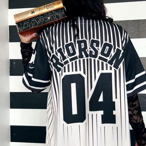 May include: A white and black striped baseball jersey with the name "RIORSON" and the number "04" printed on the back.