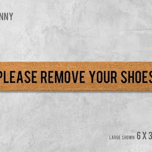 a rectangular sign with the text "PLEASE REMOVE YOUR SHOES" written on it.