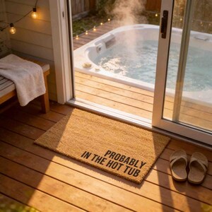 a cozy outdoor setting with a hot tub, a towel, and a door leading to a deck. The door is open, revealing the hot tub inside. The floor is covered with a rug that says "Probably in the hot tub".