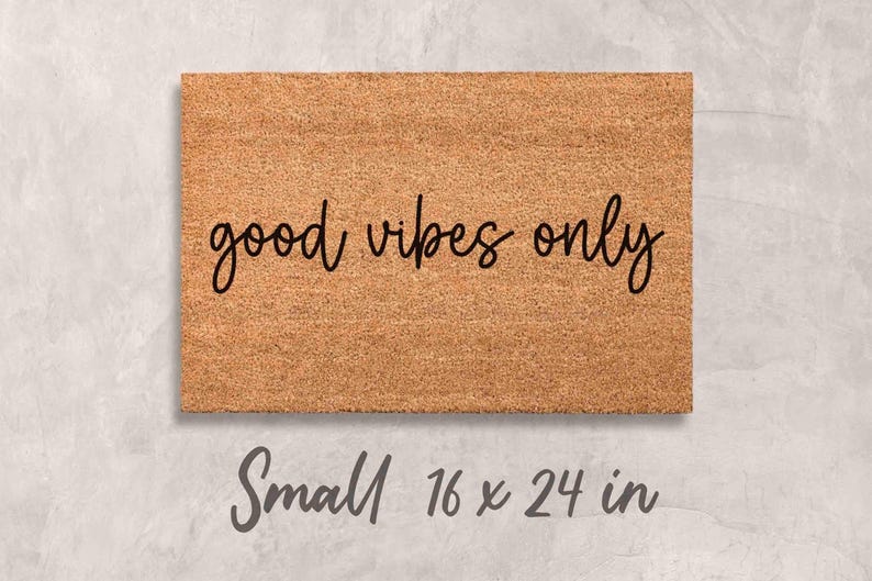 A rectangular, light brown, textured doormat with the text "good vibes only" printed on it.