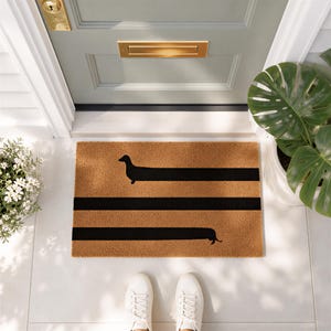 a pair of white sneakers standing on a white tiled floor, with a door and a plant nearby. The door has a gold mail slot, and there is a decorative mat with a black and orange design on the floor.