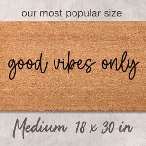 A medium-sized rectangular welcome mat with the text "good vibes only" printed on it.