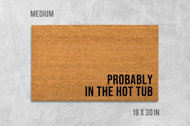 A rectangular, light brown doormat with the text "Probably in the hot tub" printed on it.