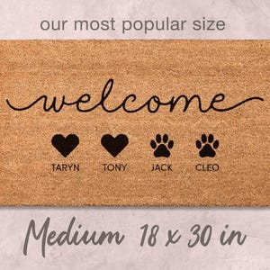 A medium-sized, rectangular, and textured doormat with the word "welcome" written on it. The doormat has four heart symbols and four paw prints, and it is described as being the "most popular size" and "medium 18 x 30 in".