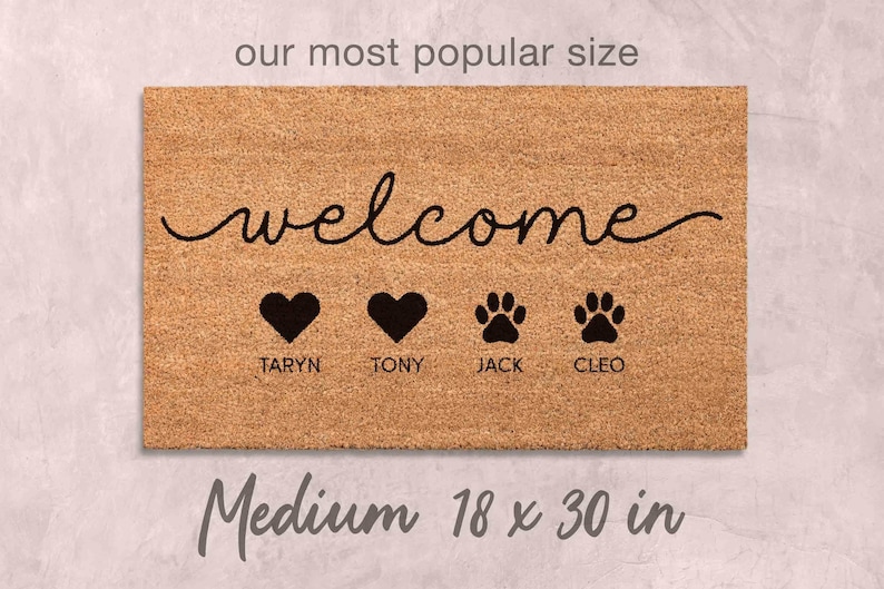A medium-sized, rectangular, and textured doormat with the word "welcome" written on it. The doormat has four heart symbols and four paw prints, and it is described as being the "most popular size" and "medium 18 x 30 in".