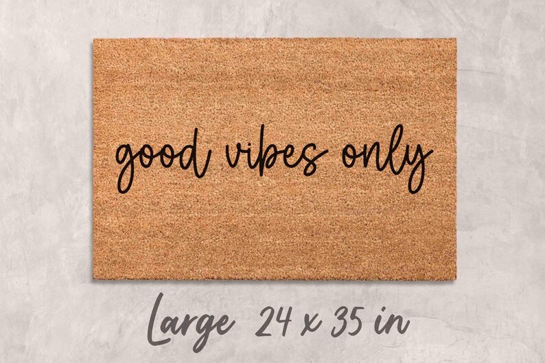 A rectangular, light brown, textured doormat with the text "good vibes only" printed on it.