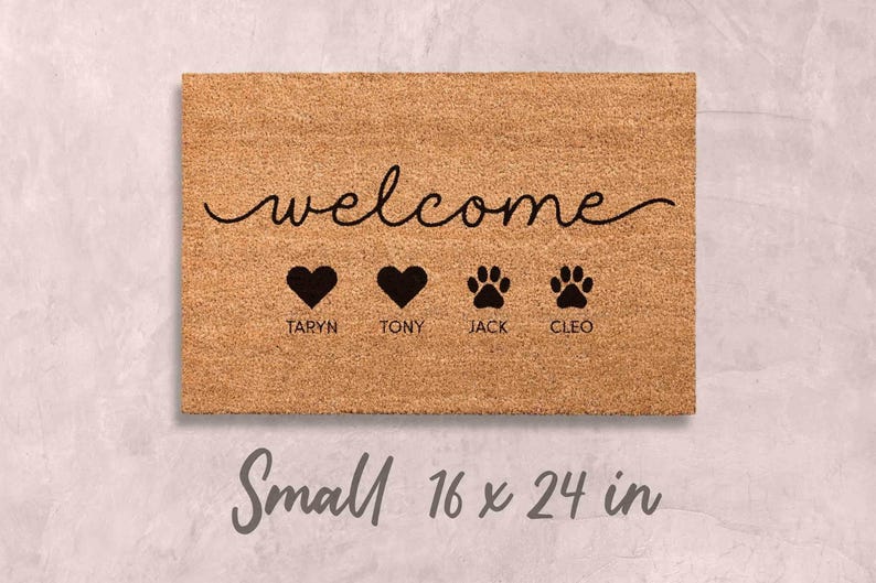 A welcome mat with the word "welcome" written on it, along with three heart symbols and the names "TARYN, TONY, JACK, CLEO". The mat is described as small, measuring 16 x 24 inches.