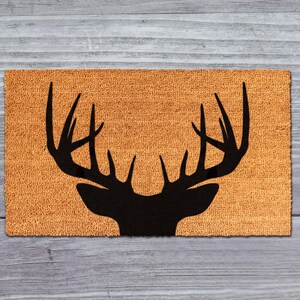 A mat with a silhouette of a deer head and antlers printed on it, placed on a wooden surface.
