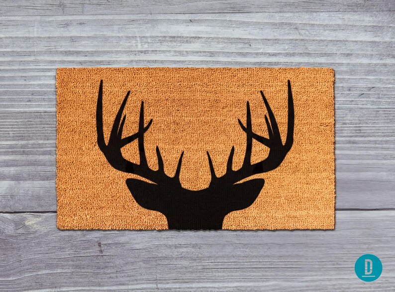 A mat with a silhouette of a deer head and antlers printed on it, placed on a wooden surface.