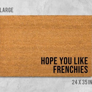 A large rectangular welcome mat with the text "HOPE YOU LIKE FRENCHIES" printed on it.