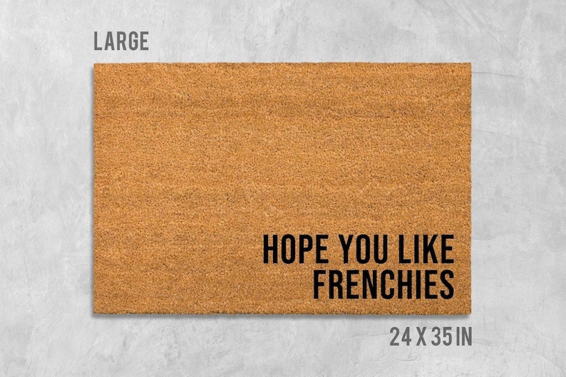 A large rectangular welcome mat with the text "HOPE YOU LIKE FRENCHIES" printed on it.