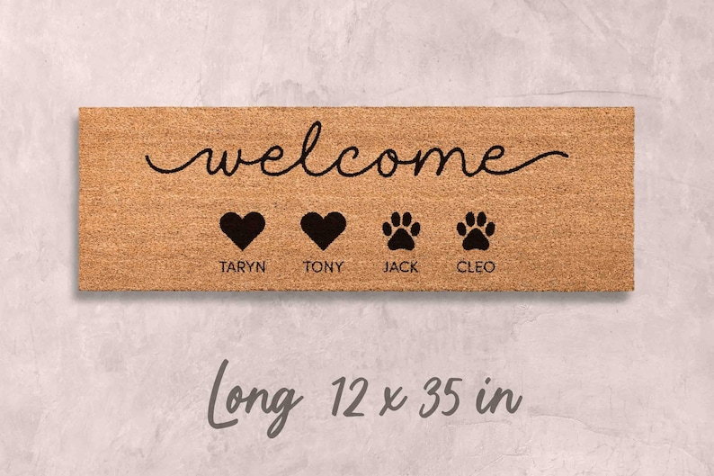 A wooden door mat with the word "welcome" written on it, along with four heart symbols and four paw prints. The mat is described as being long, 12 x 35 inches in length.