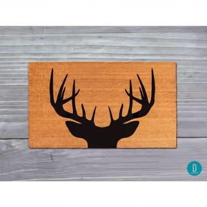 a wooden surface with a black silhouette of a deer head with antlers.