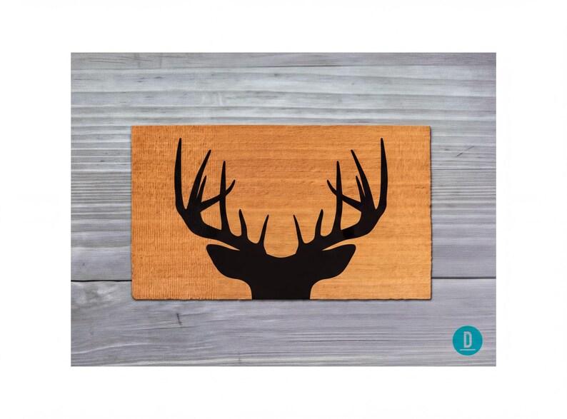 a wooden surface with a black silhouette of a deer head with antlers.