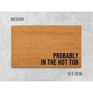 a rectangular, textured door mat with the text "Probably in the hot tub" printed on it.