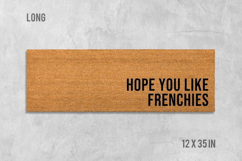 a rectangular, brown, textured doormat with the text "HOPE YOU LIKE FRENCHIES" printed on it.
