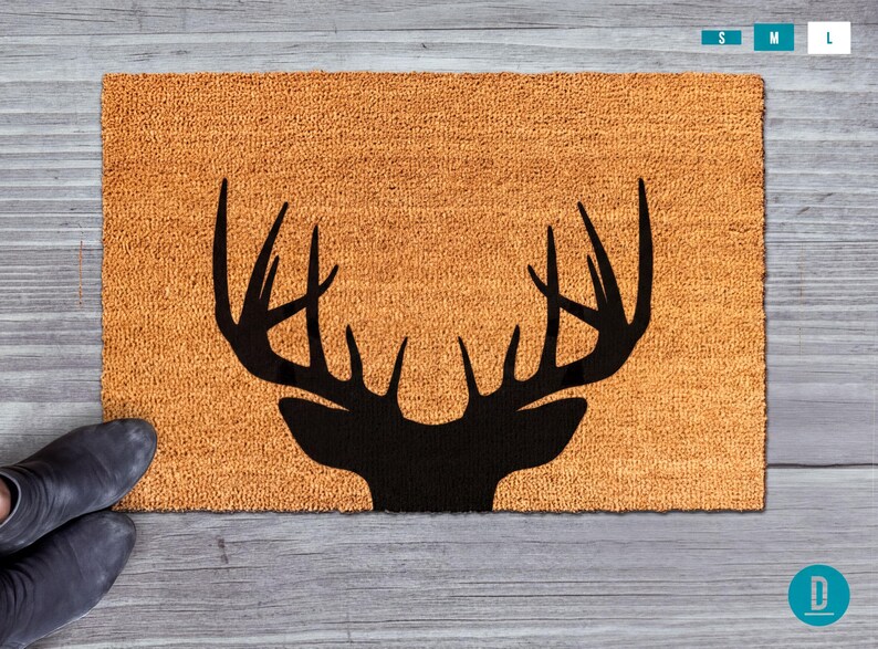 A pair of black boots is placed next to a brown, textured area rug with a black silhouette of a deer's head.