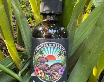 Puede incluir: Una botella de vidrio marrón con un cuentagotas negro, etiquetada como "HONOKUA-HERBALS". La etiqueta presenta una colorida ilustración de hongos, flores y una puesta de sol. El texto debajo dice "Chaga & Frankincense Radiance Serum Botanical Oil Infusion."