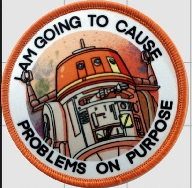 May include: A white and orange round patch with the text "I am going to cause problems on purpose" around the edge. The center of the patch features a cartoon image of a droid with a red and white body.