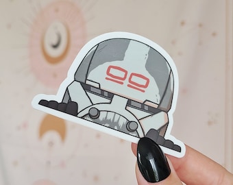 May include: A white and gray sticker of a cartoon stormtrooper with red markings on its helmet. The sticker is on a white background.