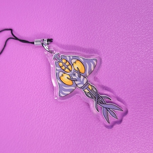 May include: A purple and white striped, cartoon-style, deep sea creature charm with yellow eyes. The charm is attached to a black string.