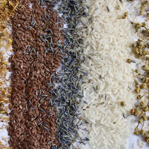 May include: Four rows of different dried ingredients, including yellow calendula petals, brown flax seeds, purple lavender buds, and white rice.