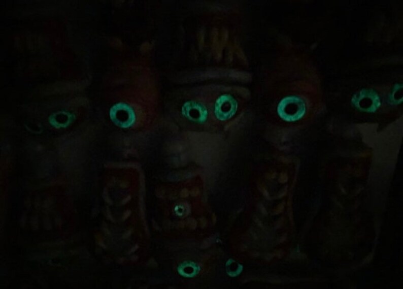 May include: A group of five small, dark figures with glowing green eyes. The figures are made of a dark material and have a slightly creepy appearance.
