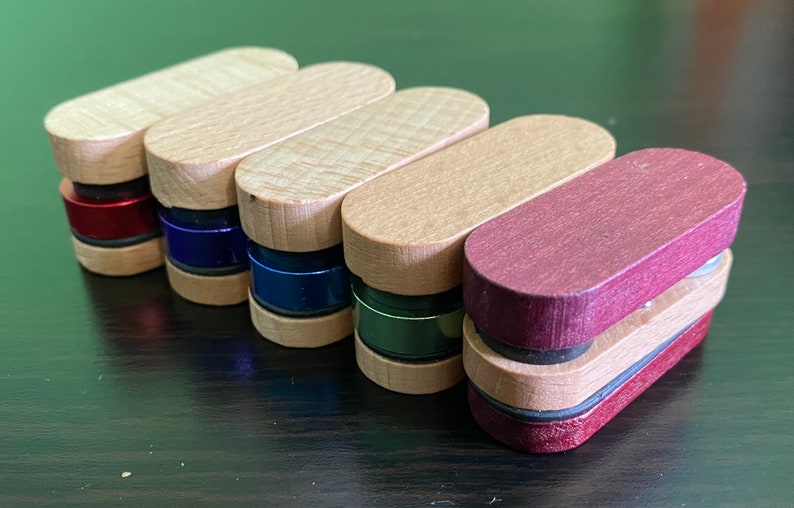 May include: Six wooden containers with different colored lids. The lids are red, blue, teal, green, and burgundy. The containers are stacked on top of each other.