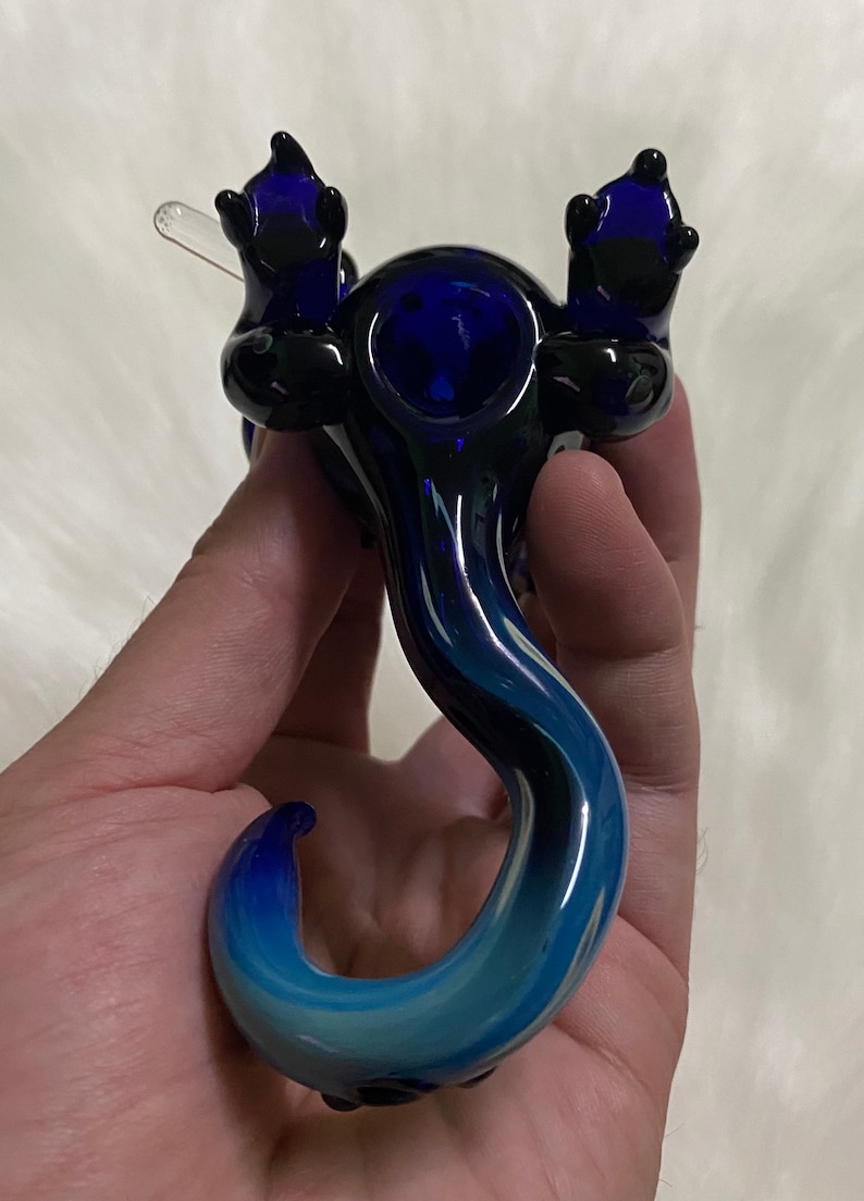 May include: A blue and black glass pipe shaped like a dragon with a bowl on its back and a long tail.