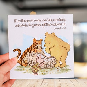 K&ouml;nnte beinhalten: Eine Karte zum Thema Winnie Puuh mit einem Zitat aus dem Buch: "Wenn ich richtig liege, ist ein neues Baby wahrscheinlich das gro&szlig;artigste Geschenk, das man sich vorstellen kann." Die Karte zeigt Winnie Puuh, Tigger und Ferkel, die ein Baby in einem Korb betrachten.