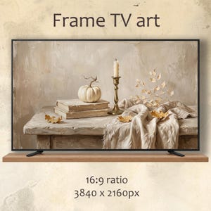 Può includere: Uno schermo digitale che mostra una natura morta con una zucca bianca su due libri impilati, un candelabro in ottone con una candela e un panno drappeggiato con foglie secche. Il testo recita Frame TV art, 16:9 ratio, 3840 x 2160px.