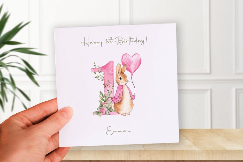 Watercolor Peter Rabbit birthday PNG clipart set with pink jacket bunny, heart balloon, greenery and floral number 1, 2 and 3 designs, shown on a baby bodysuit mockup.