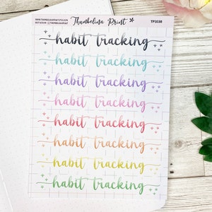 May include: A sheet of rainbow-colored habit tracker stickers with the text "habit tracking" repeated eight times. The stickers are on a white background with a grid pattern.