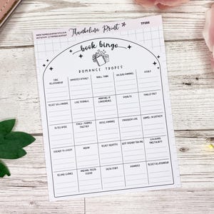 May include: A printable book bingo card with a black and white design. The card features a list of romance tropes, including "fake relationship", "enemies to lovers", "love triangle", and "second chance".
