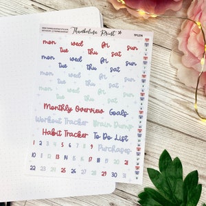 May include: A sheet of colorful planner stickers with various labels, including "Monthly Overview", "Goals", "Workout Tracker", "Brain Dump", "Habit Tracker", "To Do List", and "Purchases". The stickers also include days of the week and numbers 1 through 31.